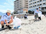 丁寧に海岸のごみを拾う参加者ら
