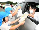 ドライバー（右）に二十世紀梨やチラシを手渡す園児ら＝２７日、岡山県真庭市蒜山下長田の蒜山展望台