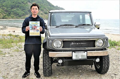  開催会場で来場を呼びかける野沢社長＝３日、岩美町大谷の大谷海岸（画像の一部を加工しています） 