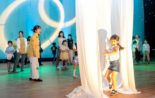 宇宙空間に見立てたステージを楽しむ親子連れら