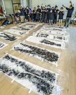 　ワークショップで出来上がった作品を前にする参加者ら。大きな布に、それぞれの凝りが表現された＝２０２５年１月、大阪府茨木市（撮影・藤井保政）