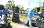 駅前広場の世界妖怪会議のコーナーでブロンズ像の布がけや落ち葉清掃に取り組む社員ら