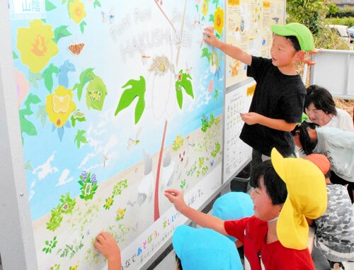 看板に昆虫や草花のマグネットを張り付ける園児ら