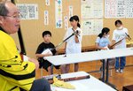 上田さん（左）の指導で三味線に挑戦する児童ら