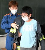 居川さん（左）が使っている防火衣を着せてもらう児童