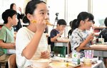 沖ギスのフライを頰張る児童＝１２日、鳥取市若葉台南２丁目の若葉台小