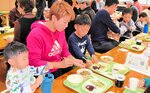 地元産の食材を使った給食を試食する親子＝香美町小代区実山の小代小
