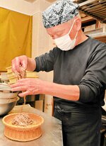 ゆでた十割そばを丁寧にざるに盛り付ける安藤さん＝豊岡市日高町栗栖の道の駅神鍋高原