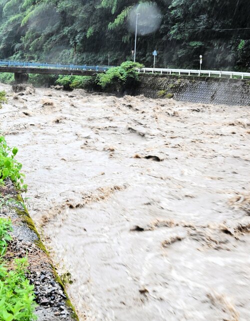 茶色の濁流が勢いよく流れる佐治川＝15日午前10時26分、鳥取市佐治町