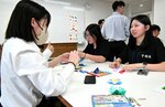 鳥取敬愛高の生徒（左）と一緒に折り紙を楽しみ会話を弾ませる亨碩高の生徒