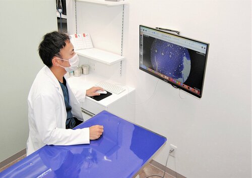 診察台で機器を操作する村井院長