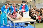 来場者の前でクロマグロをさばく割裁人たち＝１８日、鳥取県境港市昭和町の県営境港水産物地方卸売市場２号上屋