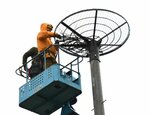 高所作業車に乗り、設置した巣台に枝や稲わらを敷き詰めていく作業員＝１３日、八頭町内
