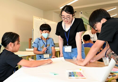 課題解決に向けたアイデアを紙に書く参加者ら