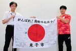  激励の寄せ書きで埋まった国旗を手に活躍を誓う高橋選手（右）＝２１日、愛知県豊田市のトヨタスポーツセンター 