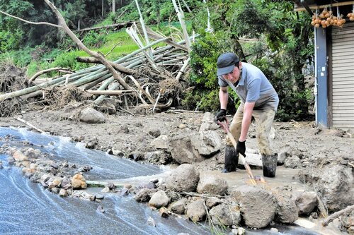 【土砂撤去】裏山が崩落し、車庫前の土砂をかき出す住民＝１６日午後１時１０分、鳥取市佐治町高山