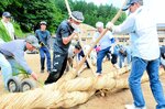 力を合わせて大綱を編む住民たち＝３日、新温泉町湯の温泉小グラウンド