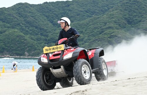 ＡＴＶと独自開発したビーチクリーナーでごみを回収する参加者