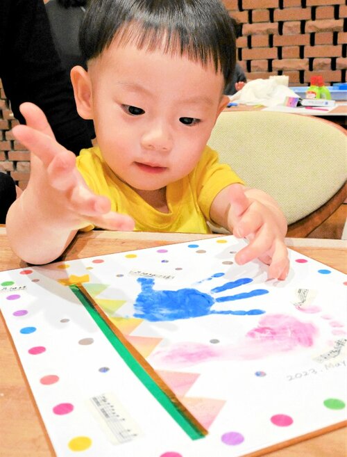 手形や足形のこいのぼりをシールで飾り付ける子ども