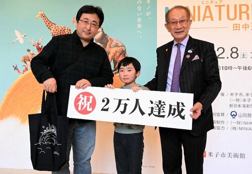 杉原理事長（右）から記念品が贈られた、２万人目の来場者の常世田さん親子＝９日、米子市美術館