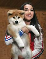 　２０１８年５月、贈呈された秋田犬の子犬を抱き、笑顔のアリーナ・ザギトワさん。「マサル」と名付けられた＝モスクワ（共同）