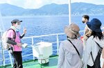 ジオパーク専門員（左端）の解説を聞きながら絶景を楽しむ体験クルージング＝昨年８月、香美町沖