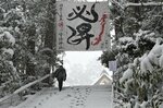 段差が分からなくなるほど降雪した階段を上り、拝殿に向かう参拝者＝24日正午、宇倍神社