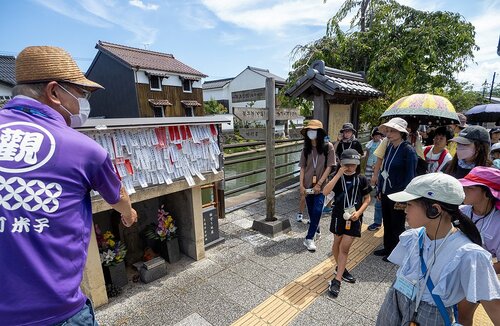 観光ガイド（左）の解説で加茂川沿いの地蔵を巡る参加者ら＝３０日、米子市内町