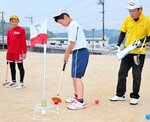 協会員（右）の指導を受けながら新しいクラブを使ってプレーする児童ら