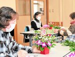 お祝いの気持ちを込めてフラワーアレンジメントを作るメンバーたち＝７日、香美町小代区実山の小代区地域連携センター