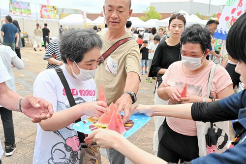 振る舞われたスイカを手に取る来場者＝２２日、倉吉市のエースパック未来中心ふれあい広場