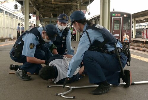 訓練で不審者役を取り押さえる警察官＝２７日、ＪＲ鳥取駅