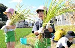刈り取った稲を手に笑顔を見せる園児