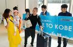 　国際チャーター便の就航が始まった神戸空港に到着し、関係者の出迎えに笑顔を見せる乗客＝１８日午前