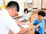 担任から通知表を受け取る児童＝１９日、香美町香住区余部の余部小