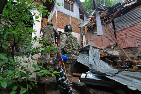　９日、インドのジャム・カシミールで、パキスタン軍に破壊された建物付近を歩く治安当局者（ゲッティ＝共同）