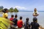 　モーレア島の海辺で子どもたちに核実験の歴史を伝えるプアライ。フランス語でなく土着のタヒチ語で語りかける＝２０２３年１１月（撮影・マネア・ファビッシュ、共同）