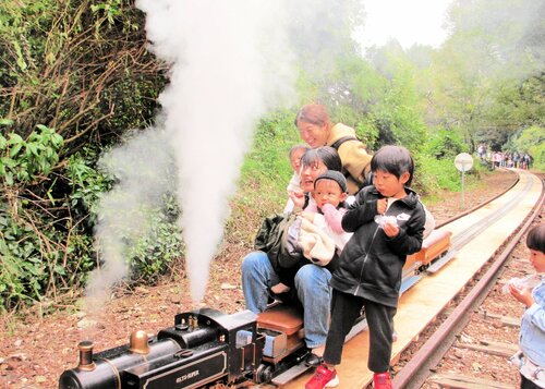 蒸気を上げて走るミニＳＬを楽しむ家族連れ