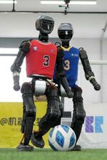 　サッカーをする「加速進化（ブースターロボティクス）」の人型ロボット＝３月、北京（共同）