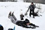 歓声を上げながら雪の斜面を腹ばいで滑る参加者＝９日、香美町村岡区宿の県立兎和野高原野外教育センター