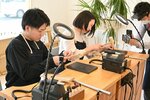 木づちを使い指輪の形を整える参加者。木附代表（右）が撮影した写真を提供するサービスも好評という