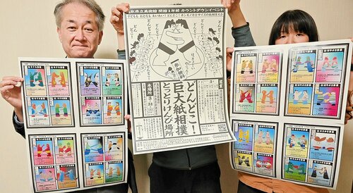  けんび場所と出場力士の紹介ポスターを掲げる梅田局長（左）ら＝２７日、倉吉市上井町１丁目の新日本海新聞社中部本社 