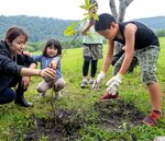 ミズナラの苗木を植樹する家族ら