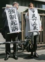 　東京電力旧経営陣３人の強制起訴が決まり、垂れ幕を掲げる「福島原発告訴団」のメンバー＝２０１５年７月、東京地裁前