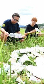漂着ごみを拾う中野さん（左）と岡田さん。「みんなで少しずつ拾ってほしい」と呼びかける＝２５日、倉吉市海田西町１丁目の天神川河川敷