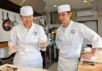 　立ち食いすし店「寿しらぼ三〇二」で、副業職人の斎藤ちひろさん（左）にアドバイスする植松隆二さん＝２０２５年１月、静岡県下田市