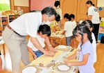 岡田さん（左）の指導を受けながら皿作りに取り組む園児ら＝新温泉町諸寄