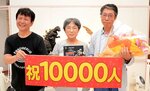 稲嶋社長（左）と並ぶ１万人目となった藤野さん夫妻＝３日、倉吉市鍛冶町１丁目の円形劇場くらよしフィギュアミュージアム