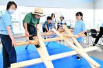 木材を組み合わせた「ダヴィンチの橋」を恐る恐る渡る子ども