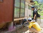 　被災した住宅を調べる山本周さん（奥）＝５月１１日、石川県輪島市